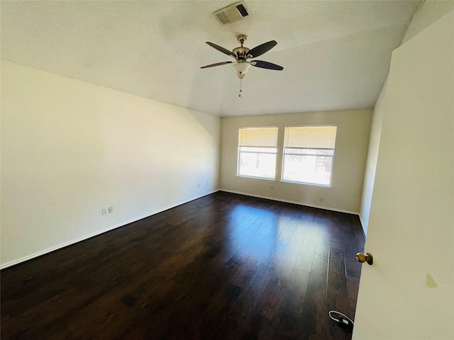 empty room featuring visible vents, dark wood finished floors, and a ceiling fan