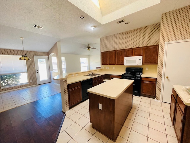 kitchen featuring a textured ceiling, a peninsula, a sink, light countertops, and black appliances