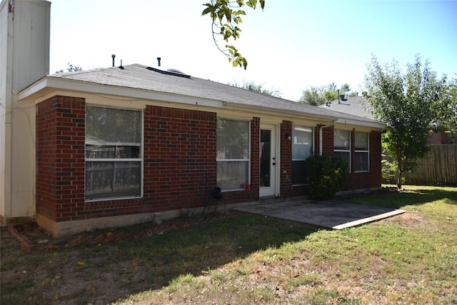 ranch-style house with a patio, brick siding, a front yard, and fence