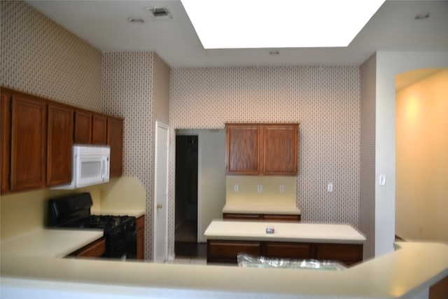 kitchen with light countertops, visible vents, white microwave, black range with gas cooktop, and wallpapered walls