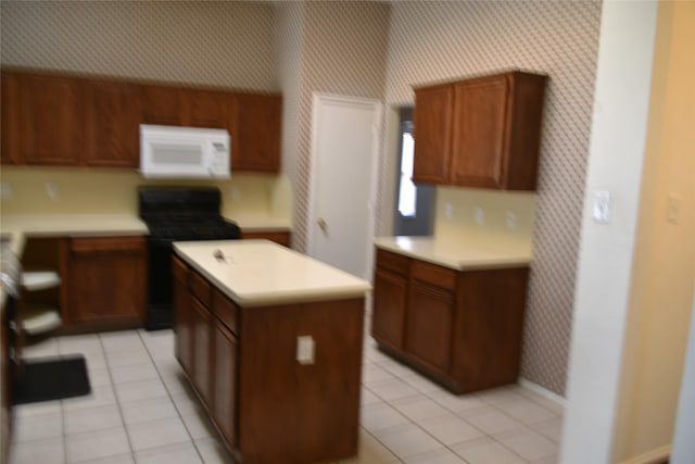 kitchen with white microwave, a kitchen island, light countertops, black range with gas stovetop, and wallpapered walls