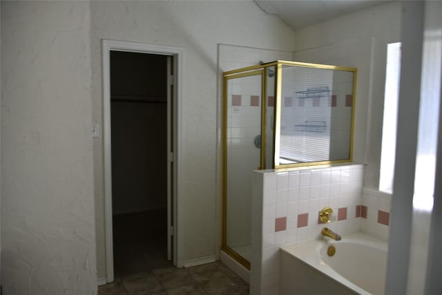 bathroom featuring a textured wall, tile patterned flooring, vaulted ceiling, a shower stall, and a bath