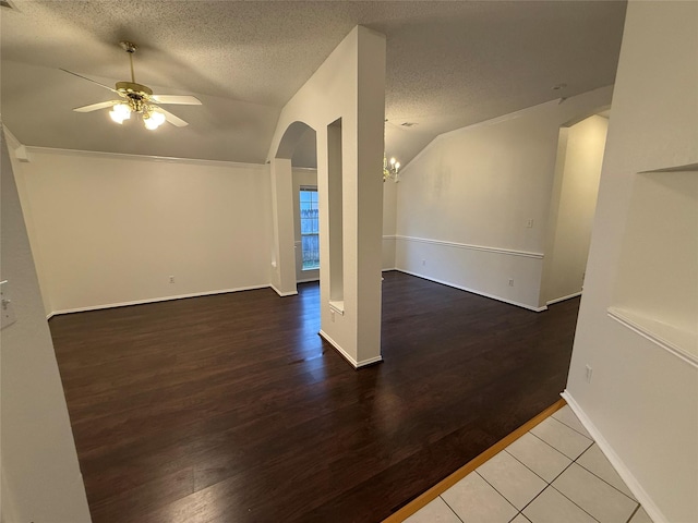 interior space featuring lofted ceiling, arched walkways, a textured ceiling, ceiling fan with notable chandelier, and wood finished floors