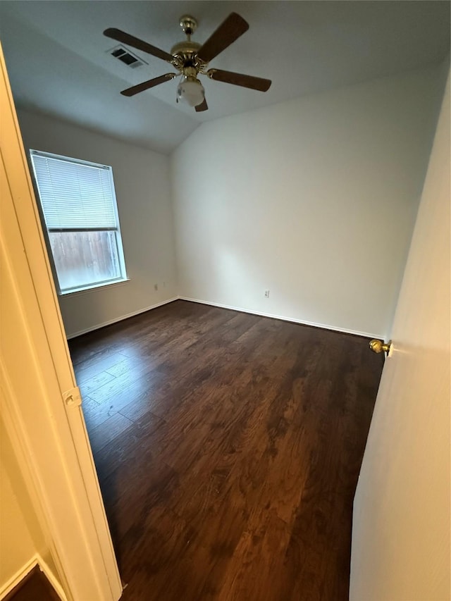 empty room with lofted ceiling, ceiling fan, visible vents, and dark wood finished floors