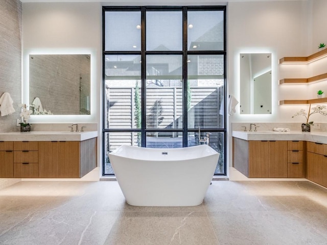 full bathroom featuring a wall of windows, a soaking tub, two vanities, and a sink