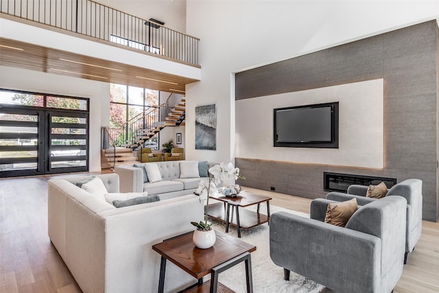 living room with stairs, a high ceiling, and light wood-style floors