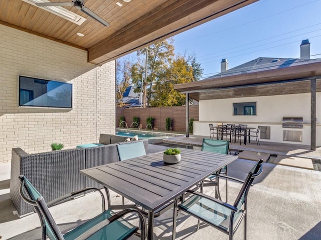 view of patio with area for grilling, outdoor dining space, ceiling fan, fence, and an outdoor kitchen