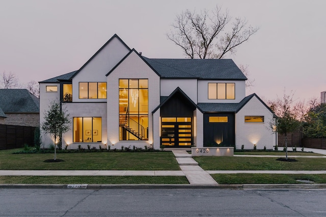 view of front of house featuring brick siding, stucco siding, and a yard