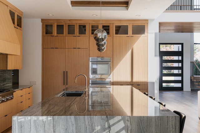 kitchen with a tray ceiling, stone countertops, stainless steel appliances, a sink, and modern cabinets