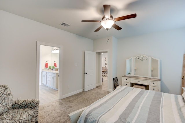 bedroom featuring light colored carpet, visible vents, ensuite bathroom, a ceiling fan, and baseboards