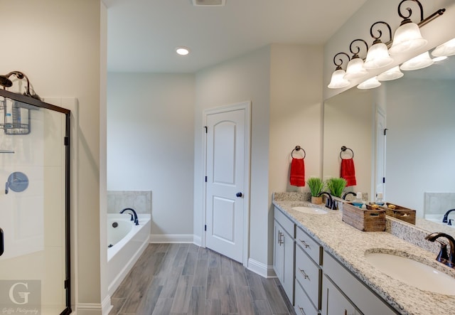 bathroom featuring a bath, a shower stall, a sink, and wood finished floors