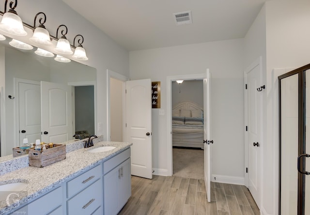 full bathroom featuring double vanity, visible vents, connected bathroom, wood finished floors, and a sink