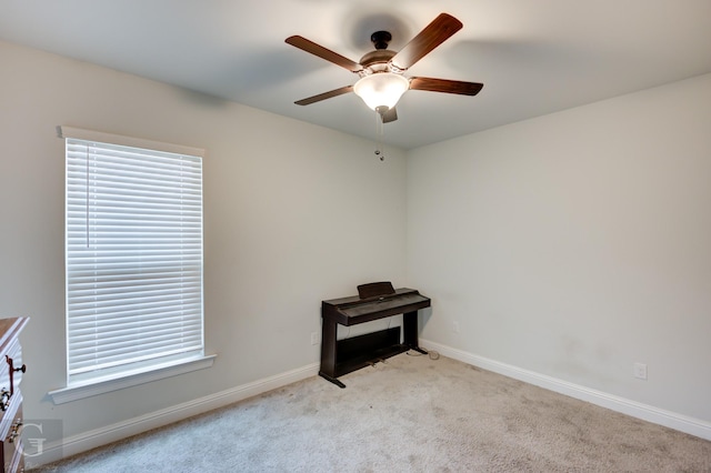 misc room featuring a ceiling fan, light carpet, and baseboards