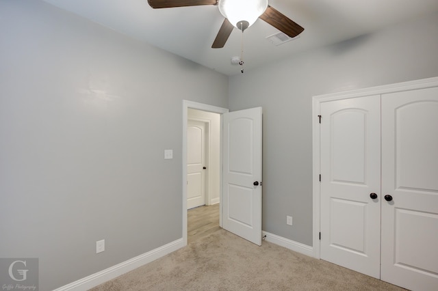 unfurnished bedroom with baseboards, a closet, a ceiling fan, and light colored carpet