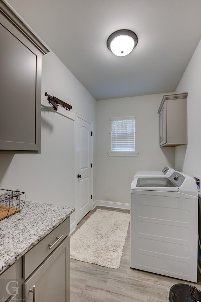 laundry room with baseboards, cabinet space, independent washer and dryer, and light wood finished floors