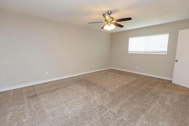 carpeted empty room with ceiling fan and baseboards