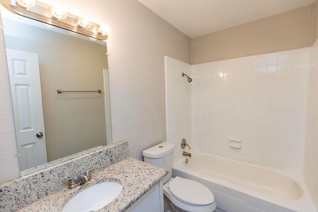 bathroom with toilet,  shower combination, a textured wall, and vanity