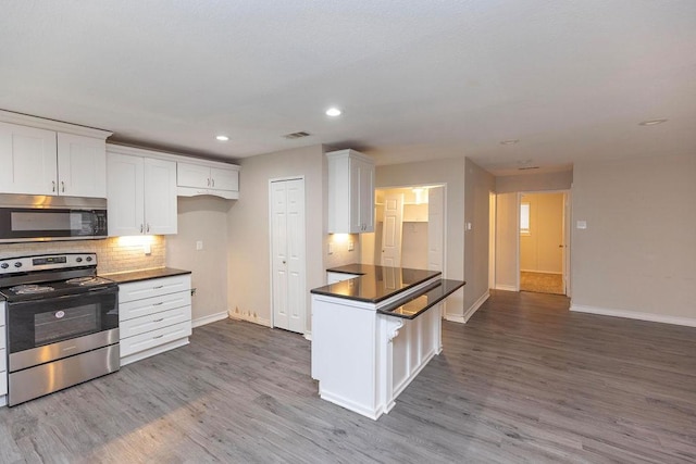 kitchen with dark countertops, dark wood-style floors, white cabinetry, and appliances with stainless steel finishes