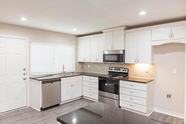 kitchen featuring appliances with stainless steel finishes, light wood-style floors, white cabinets, and a sink