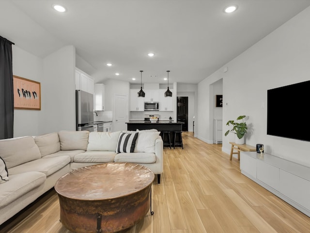 living area featuring light wood-type flooring, baseboards, and recessed lighting