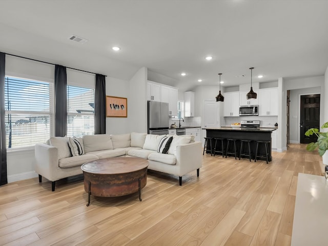 living area featuring light wood-style flooring, visible vents, and recessed lighting