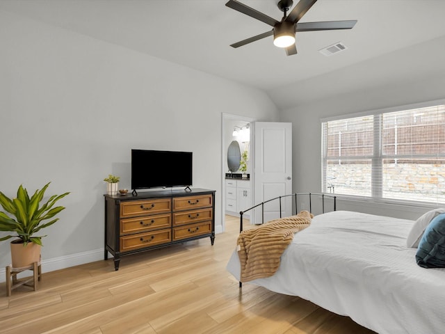 bedroom featuring visible vents, light wood-style floors, connected bathroom, vaulted ceiling, and baseboards