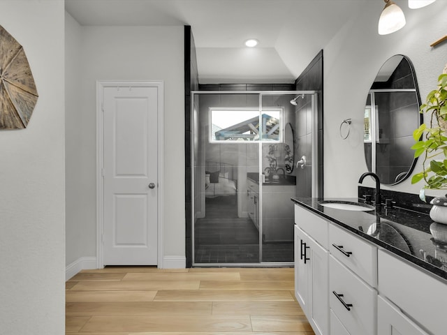 full bath with wood finish floors, a shower stall, vanity, and baseboards