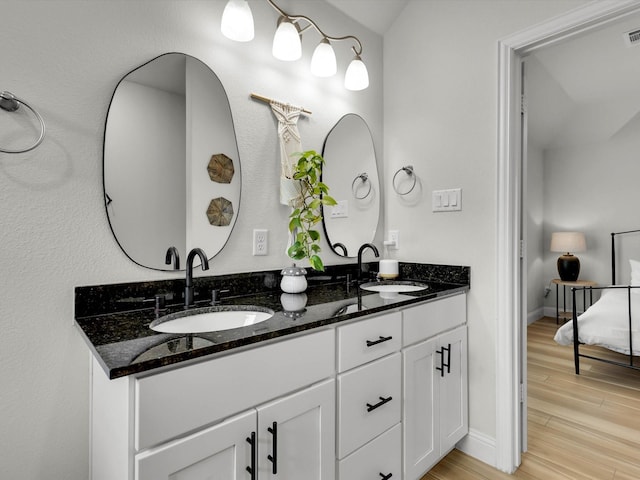 full bathroom with double vanity, wood finished floors, a sink, and visible vents