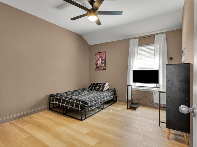 bedroom featuring baseboards, vaulted ceiling, and wood finished floors