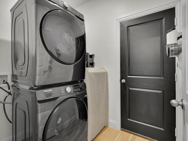 clothes washing area with light wood-style floors, stacked washer / dryer, and laundry area