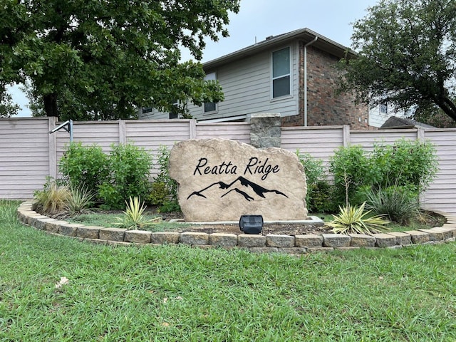 community / neighborhood sign featuring a lawn and fence