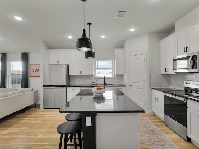 kitchen featuring stainless steel appliances, light wood finished floors, a kitchen island, and visible vents