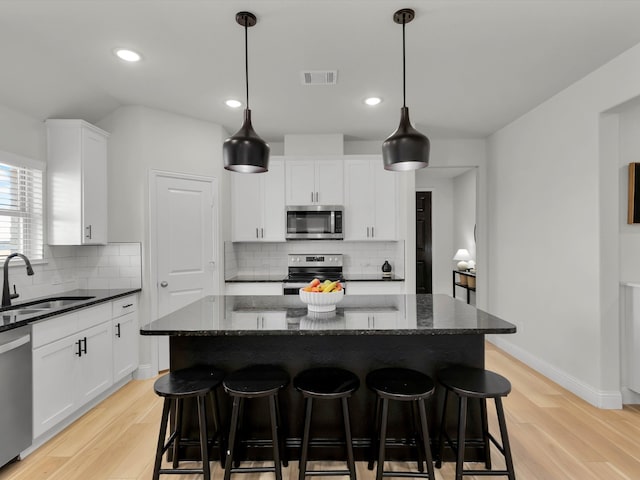 kitchen featuring stainless steel appliances, a breakfast bar area, a sink, and a center island