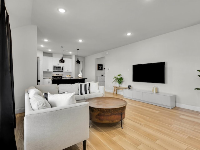 living area featuring light wood finished floors, baseboards, and recessed lighting