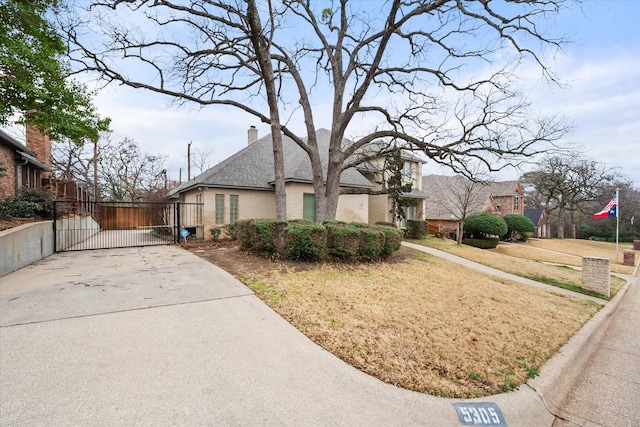 view of front of property featuring a gate, brick siding, a chimney, and a front lawn