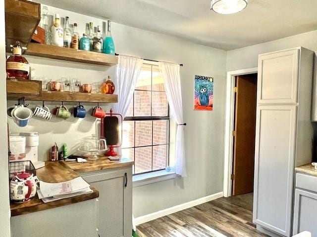 interior space with a bar, wood finished floors, and baseboards