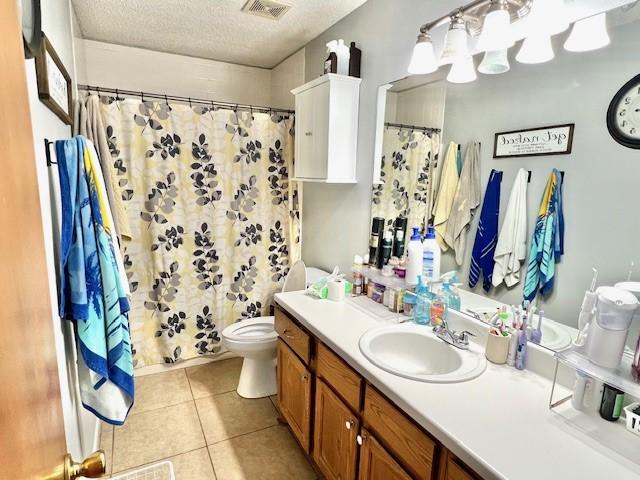 bathroom featuring visible vents, toilet, a textured ceiling, vanity, and tile patterned floors