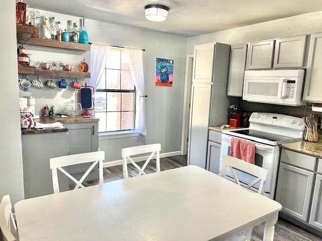 kitchen featuring white appliances, dark wood-type flooring, baseboards, light countertops, and gray cabinets