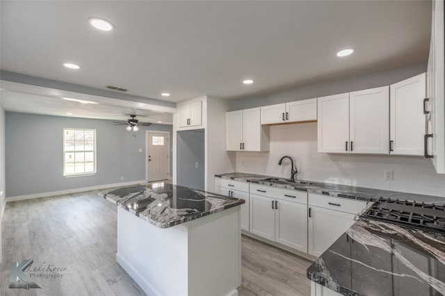 kitchen featuring light wood-style flooring, white cabinetry, a ceiling fan, backsplash, and dark stone countertops