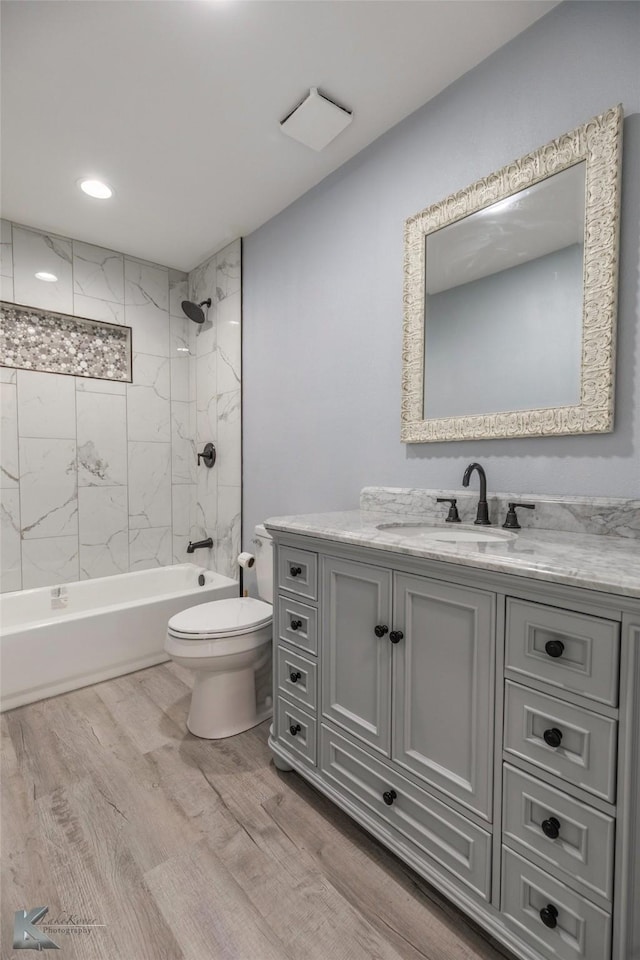 bathroom featuring vanity, bathing tub / shower combination, wood finished floors, and toilet