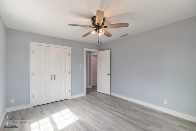 unfurnished bedroom featuring visible vents, baseboards, ceiling fan, wood finished floors, and a closet