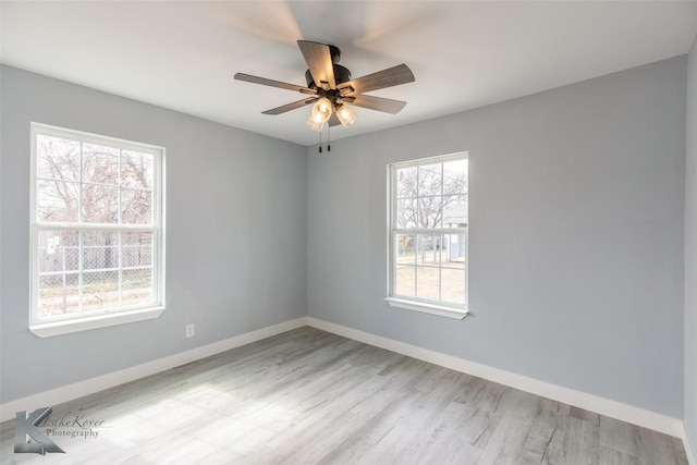 unfurnished room with wood finished floors, a ceiling fan, and baseboards