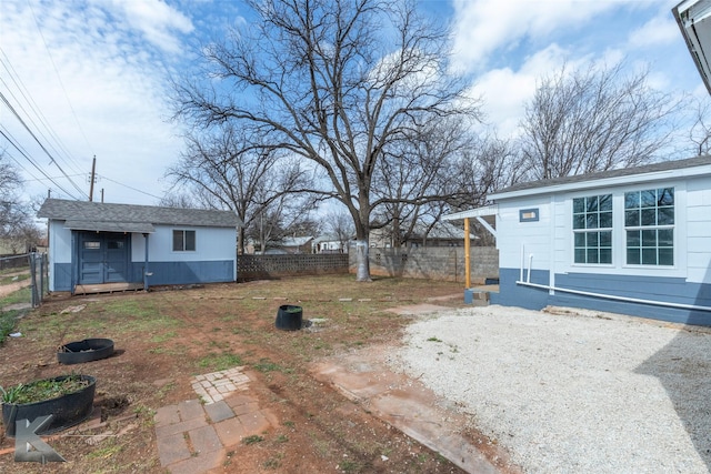 view of yard featuring driveway, an outdoor structure, and fence