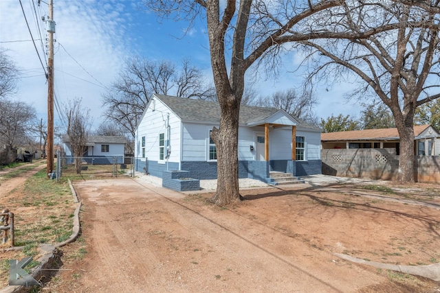 view of front of house with driveway, a shingled roof, and fence