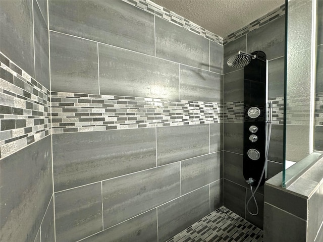 full bath with a tile shower and a textured ceiling