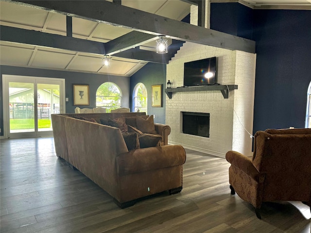 living room featuring lofted ceiling with beams, a brick fireplace, wood finished floors, and a wealth of natural light