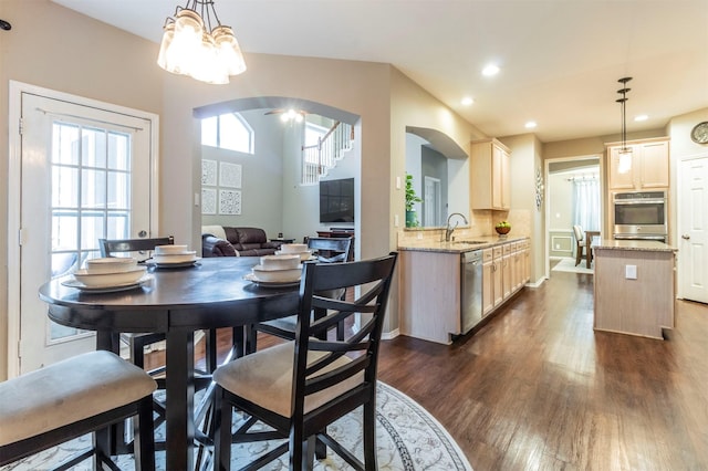 dining room with an inviting chandelier, dark wood-type flooring, recessed lighting, and arched walkways