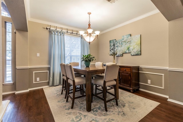 dining space featuring crown molding, wood finished floors, and wainscoting