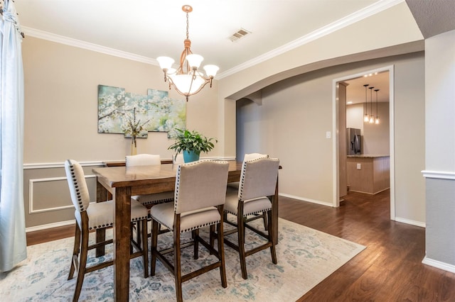 dining room with visible vents, wood finished floors, crown molding, baseboards, and a chandelier