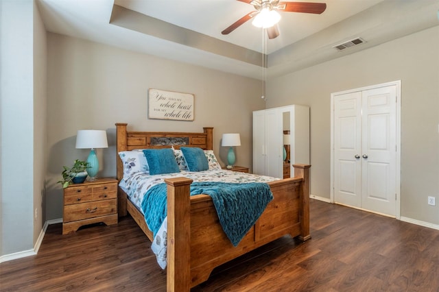 bedroom featuring visible vents, a raised ceiling, baseboards, and dark wood-style floors